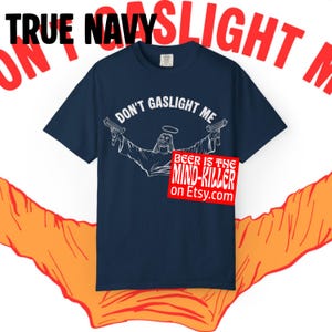 May include: True navy blue t-shirt with the text "DON'T GASLIGHT ME" and a graphic of a figure holding two guns. A red rectangle with the text "BEER IS THE MIND-KILLER on Etsy.com" is also visible.