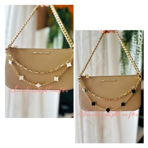 Puede incluir: Dos bolsos de cuero marrón con cadenas y abalorios dorados. Los bolsos tienen el logotipo de Michael Kors en la parte delantera. Un bolso tiene abalorios de trébol blanco y el otro tiene abalorios de trébol negro.