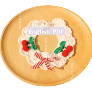May include: White crocheted collar with red and green cherry accents and a red and white gingham bow. The collar is on a wooden surface. The text "English PDF" is visible in the image.