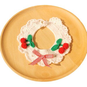 May include: White crocheted collar with a red and white gingham bow and two green and red cherry embellishments.