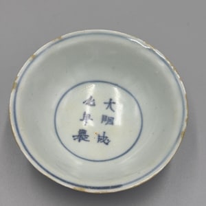 Peut inclure: Petit bol rond en porcelaine antique, intérieur bleu clair et bordure bleu foncé. Le bol présente des caractères chinois dans un cercle bleu central. Le bord extérieur est de couleur or délavé.