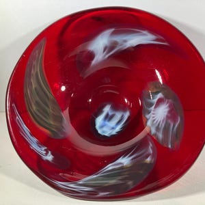 May include: A red glass bowl with white and brown swirls. The bowl is approximately 8 inches in diameter.