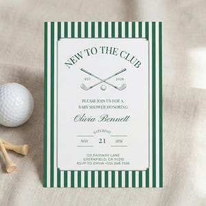 Printable golf themed baby shower invitation with green striped border displayed upright on soft linen fabric, styled with a white golf ball and wooden tees for a classic country club look.