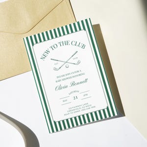 Printable baby shower invitation with green striped border displayed upright on soft linen fabric, styled with a white golf ball and wooden tees for a classic country club look.