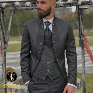 May include: A dark gray tuxedo with a floral pattern, featuring a vest, jacket, and trousers. The jacket has decorative buttons and a high collar. The outfit includes a tie and a pocket watch chain. The text "SHEKLY TUX" is visible.