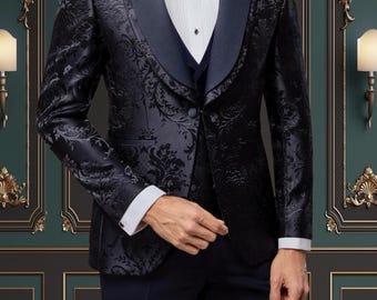 Puede incluir: Una chaqueta de esmoquin negra con cuello de chal de satén y un estampado floral. La chaqueta se combina con un chaleco azul marino y pantalones a juego.