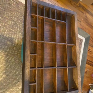 May include: A rectangular wooden printer's tray featuring a dark brown finish and multiple internal compartments of varying sizes. The organizer has a sturdy frame with vertical and horizontal dividers creating a grid pattern for storage.