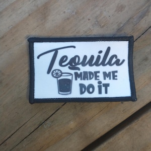 Puede incluir: Parche blanco con borde negro y texto que dice "Tequila made me do it". Una ilustración en blanco y negro de un vaso de chupito con una rodaja de lima está al lado del texto.