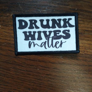 Puede incluir: Parche blanco con texto negro que dice "Drunk Hives Matter" en una fuente retro.
