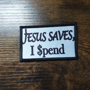 May include: White patch with black text that reads "Jesus Saves, I $pend".
