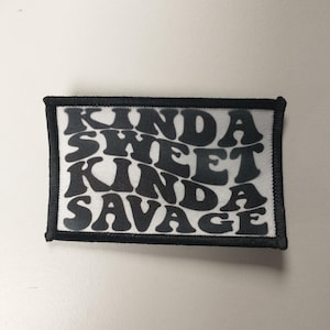 Peut inclure: Patch thermocollant noir et blanc avec le texte "Kinda Sweet Kinda Savage" dans une police rétro.