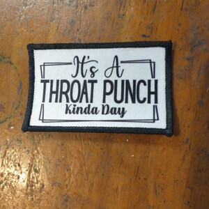 May include: White patch with black border and text that reads "It's a Throat Punch Kinda Day".