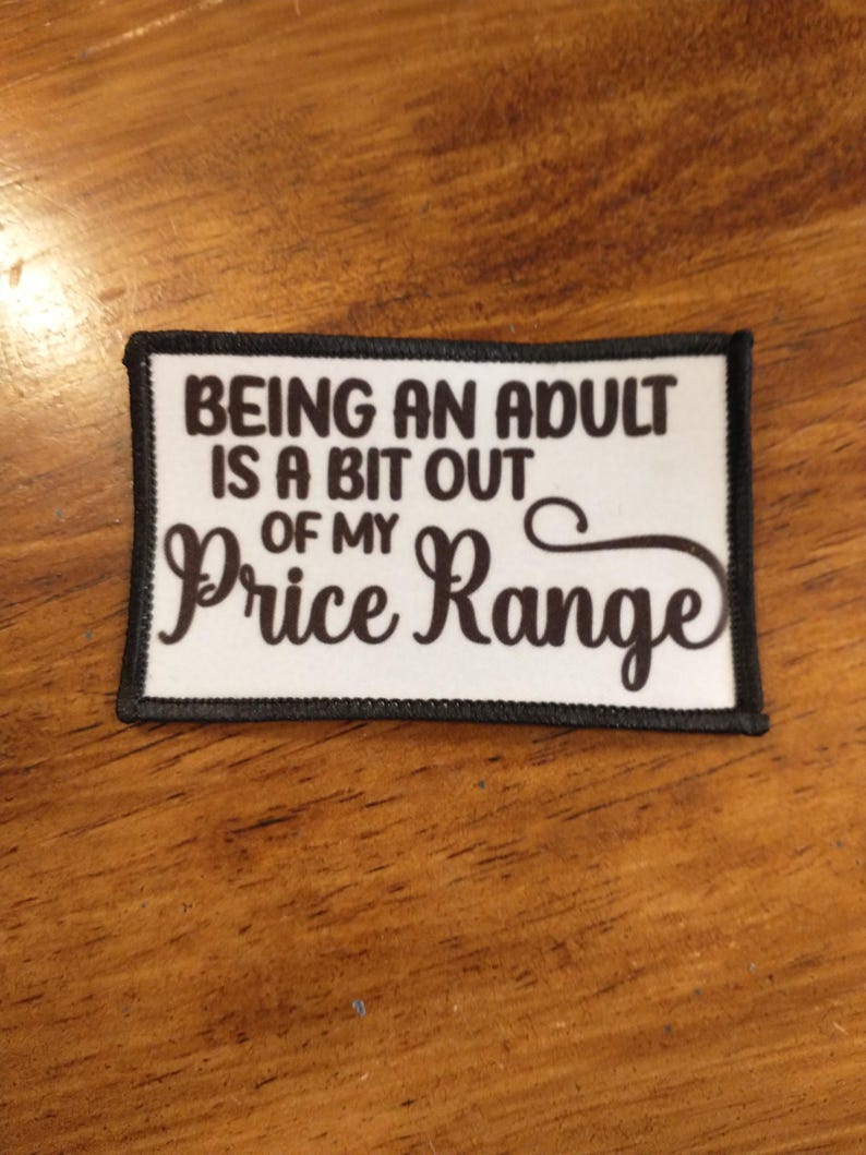 May include: White patch with black border and brown text that reads "Being an adult is a bit out of my price range".