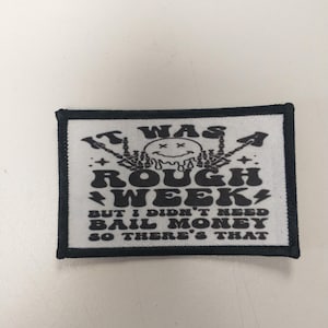 May include: Black and white embroidered patch with the text "It was a rough week, but I didn't need bail money so there's that". The patch features a cartoon skull with a smiley face and crossed bones.