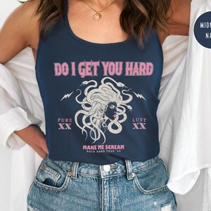 May include: A navy blue vest top with the pink text "DO I GET YOU HARD". The design includes a Medusa illustration with snakes and lightning bolts. The text "PURE XX" and "LUST XX" are also present.