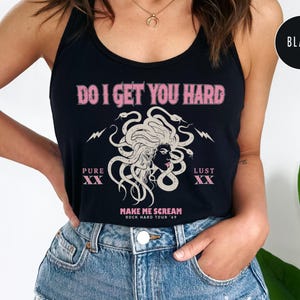 May include: Black vest top featuring the text "DO I GET YOU HARD" in pink, a Medusa illustration, and the phrases "PURE XX" and "LUST XX". The bottom of the top reads "MAKE ME SCREAM ROCK HARD TOUR '69".