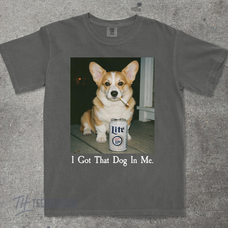 May include: Dark grey t-shirt with a graphic of a corgi dog smoking a cigarette and a Lite beer can. The text "I Got That Dog In Me" is printed below the image.