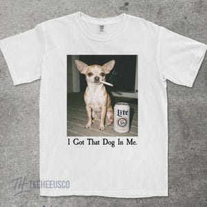 Puede incluir: Camiseta blanca con un gr&aacute;fico de un chihuahua con un cigarrillo en la boca y una lata de cerveza Lite. El texto "I Got That Dog In Me" est&aacute; impreso debajo de la imagen.