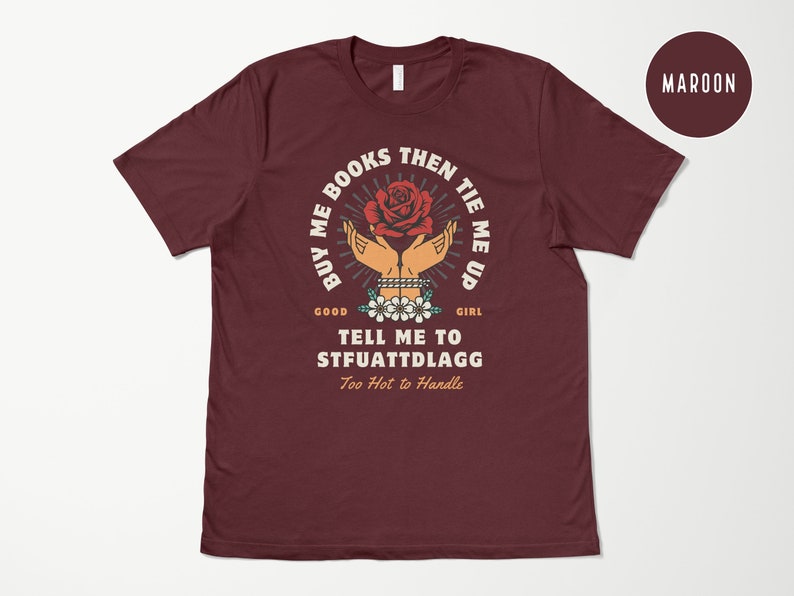 K&ouml;nnte beinhalten: Maroonfarbenes T-Shirt mit einem Motiv einer Hand, die eine rote Rose h&auml;lt, mit dem Text "BUY ME BOOKS THEN TIE ME UP GOOD GIRL TELL ME TO STFUATTDLAGG Too Hot to Handle"