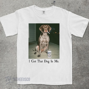 K&ouml;nnte beinhalten: Wei&szlig;es T-Shirt mit einem humorvollen Bild eines Hundes mit Zigarette im Maul und einer Bierdose. Der Text "I Got That Dog In Me" ist unter dem Bild aufgedruckt. Das Shirt ist aus weichem Material.
