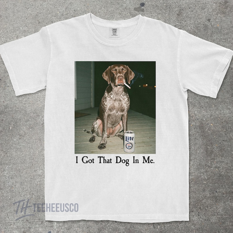K&ouml;nnte beinhalten: Wei&szlig;es T-Shirt mit einem humorvollen Bild eines Hundes mit Zigarette im Maul und einer Bierdose. Der Text "I Got That Dog In Me" ist unter dem Bild aufgedruckt. Das Shirt ist aus weichem Material.