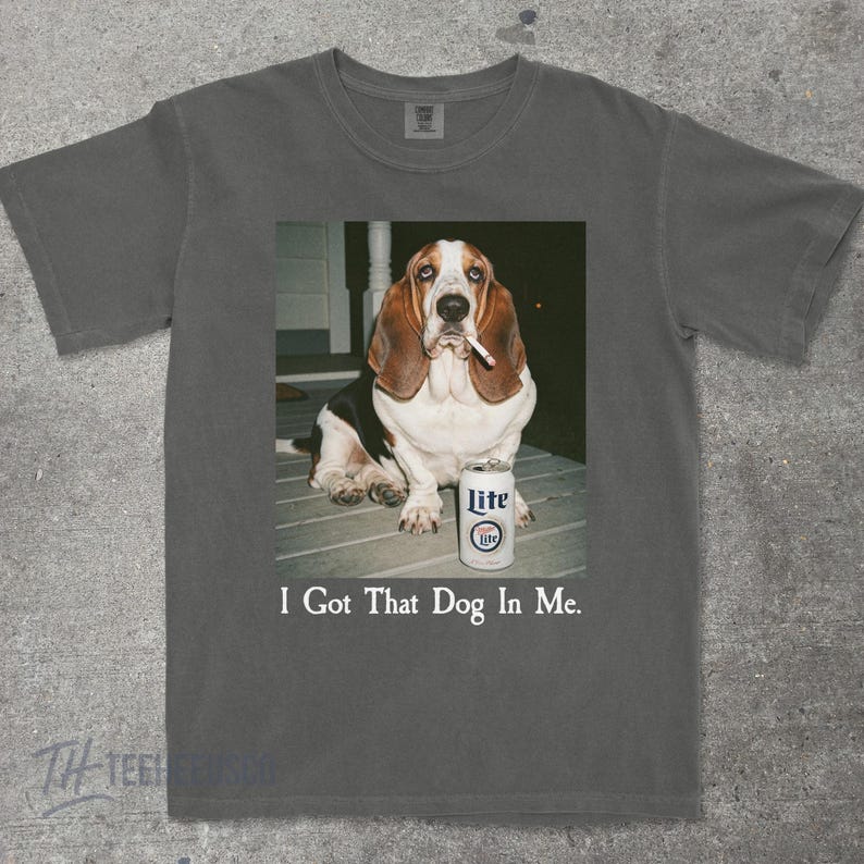 May include: Gray t-shirt featuring a graphic of a Basset Hound with a cigarette in its mouth, next to a can of Lite beer. The text "I Got That Dog In Me" is printed below the image.