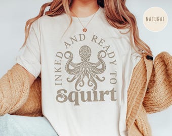 May include: A white t-shirt with a graphic of an octopus and the text "Inked and Ready to Squirt" printed on it.