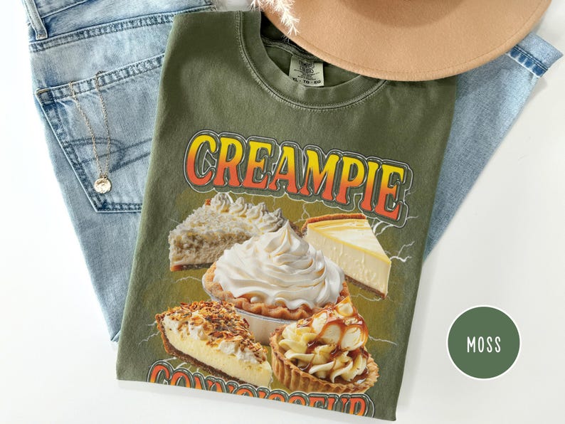 May include: Green t-shirt with the text "CREAMPIE CONNOISSEUR" in yellow and orange letters. The shirt features a graphic of four different types of pies, including a cheesecake, a cream pie, and a pecan pie.
