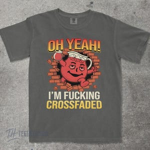 May include: Gray t-shirt with a graphic of a red Kool-Aid Man bursting through a brick wall, holding a pitcher. Text reads "OH YEAH!" and "I'M FUCKING CROSSFADED" in yellow and orange.
