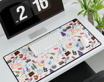 May include: A rectangular white desk mat with a black border, covered in a repeating pattern of whimsical illustrations. The design includes musical notes, guitars, lip prints, and other decorative elements. A computer keyboard and mouse sit on the mat.