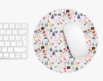 May include: A round white mousepad with a colorful pattern of various small illustrations, including a dress, a snake, a guitar, and the number 13. A white computer mouse sits on the mousepad, next to a keyboard.