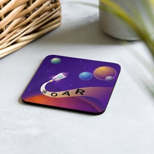 Peut inclure: Un dessous de verre carré violet et orange avec une fusée qui vole dans l'espace. La fusée laisse une traînée de fumée qui dit "SOAR". Il y a des planètes en arrière-plan.