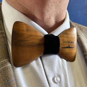 May include: A wooden bow tie with a black velvet band. The bow tie has the text "USS IOWA BB-61" and a silhouette of a ship engraved on it.