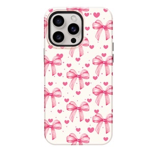 May include: A white phone case with a pink bow and heart pattern.