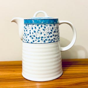 May include: White ceramic teapot with a blue and white floral pattern. The teapot has a lid and a handle.