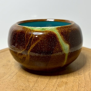 May include: A set of three ceramic mugs with a speckled, matte finish. The mugs are in shades of cream, light gray, and dark gray. Each mug has a simple, minimalist design, perfect for coffee or tea.