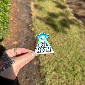 May include: A blue and white sticker with a UFO and the text "Take me to NOT-HOTH" on a triangular background.