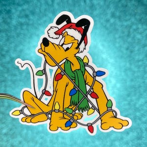 May include: A yellow cartoon dog wearing a Santa hat and a green scarf, tangled in a string of Christmas lights with red, yellow, and blue bulbs. The dog is a sticker with a white border.