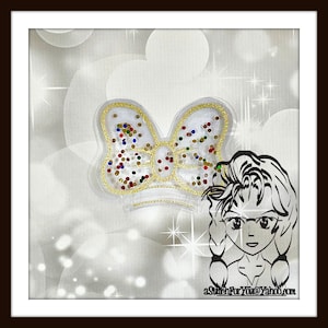 Op de afbeelding: Een witte strik met gouden versiering en kleurrijke glitteraccenten. De strik is op een witte achtergrond met een sprankelend effect.