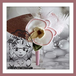 Può includere: Un fiore di orchidea in feltro bianco con cuciture rosa e foglie verdi, attaccato a un cerchietto rosa. Il cerchietto è decorato con una piuma bianca e una catena argentata.