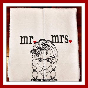 May include: Two white towels with embroidered text "mr" and "mrs" with a red heart next to each word. A cartoon image of a woman with long hair and glasses is between the words.