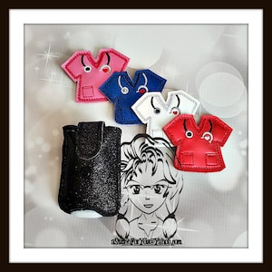 May include: A collection of colorful, miniature scrub top ornaments in pink, blue, white, and red, each with a stethoscope and heart detail. A black glittery case and a cartoon nurse graphic are also present. Text on the image reads: aStitchForYou@Yahoo.com.