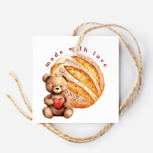 May include: A white gift tag with a brown teddy bear holding a red heart and a loaf of bread. The tag says "made with love" in red text.