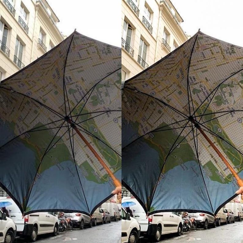 May include: A black umbrella with a map of a city printed on the inside. The umbrella is being held up in a city street.