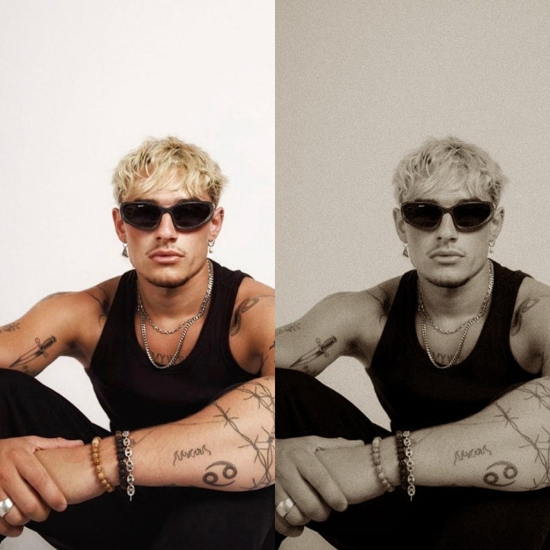 May include: A person wearing black sunglasses, a black tank top, and multiple silver necklaces. The person has tattoos on their arms and is wearing bracelets. The background is plain white.