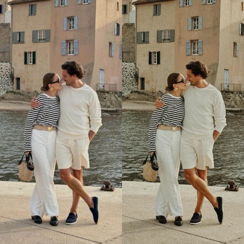 May include: A couple wearing white clothing and striped shirts are standing on a dock by the water. The man is wearing white shorts and a white sweater. The woman is wearing white pants and a black and white striped shirt. They are both wearing sunglasses.