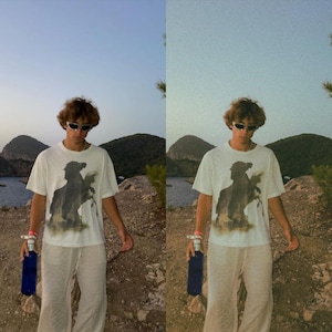 K&ouml;nnte beinhalten: Eine Person tr&auml;gt ein wei&szlig;es T-Shirt mit einem schwarz-wei&szlig;en Grafikdruck eines Pferdes und Reiters. Sie tr&auml;gt eine Sonnenbrille und eine wei&szlig;e Hose. Die Person h&auml;lt eine blaue Wasserflasche in ihrer rechten Hand.
