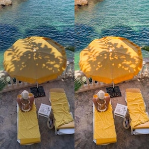 May include: Two yellow lounge chairs with yellow towels on them are positioned under a yellow umbrella with a palm tree shadow. The chairs are on a stone patio overlooking a blue body of water.