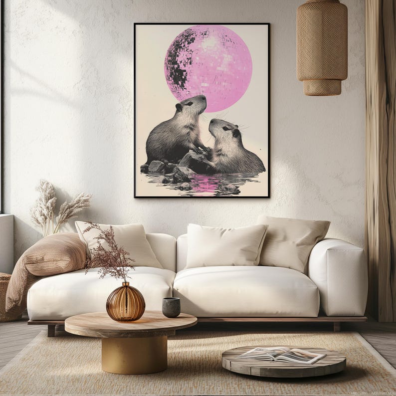 May include: A framed print of two capybaras looking up at a large pink moon. The capybaras are in a body of water with rocks and reflections.