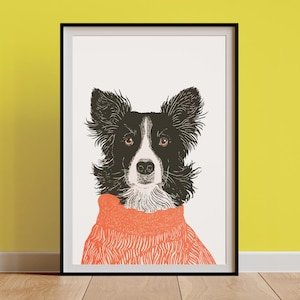 May include: A framed art print depicting a Border Collie dog illustration. The dog is rendered in black and white with brown eyes and an orange sweater. The artwork is presented on a white background, within a black frame.